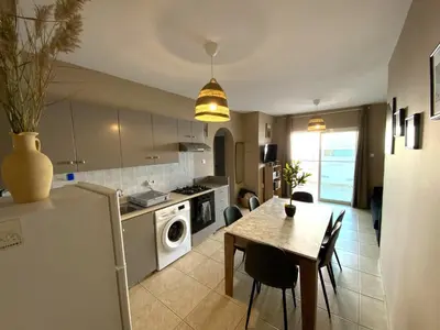 a kitchen and dining room with a table and a refrigerator at Spacious 3Apt Combo, Fast WiFi, 5Min Walk to Beach in Larnaka