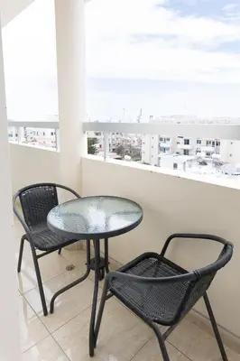 a glass table and two chairs on a balcony at Cozy Apartment with Sea View in Larnaka