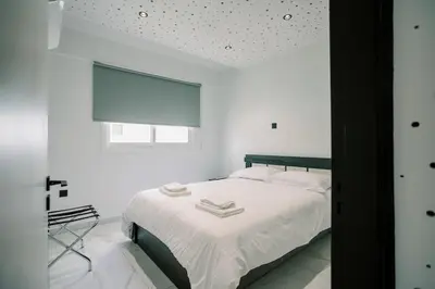 a bedroom with a bed with white sheets and a window at 2BR Amalfi Blue Apt in Larnaca - Pool & 10Min Walk to Mackenzie Beach! in Larnaka