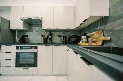 a kitchen with white cabinets and a stove at 2BR Amalfi Blue Apt in Larnaca - Pool & 10Min Walk to Mackenzie Beach! in Larnaka