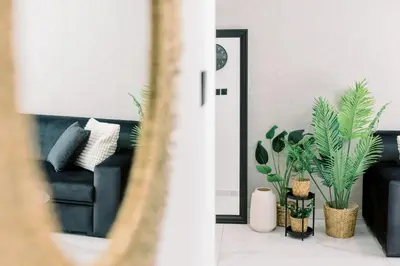 a living room with a black couch and plants at 2BR Amalfi Blue Apt in Larnaca - Pool & 10Min Walk to Mackenzie Beach! in Larnaka