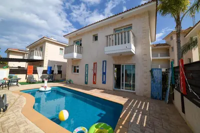 a villa with a swimming pool in front of a house at Chromata means colorful for a much-needed sunny escape, check your stay! in Protaras