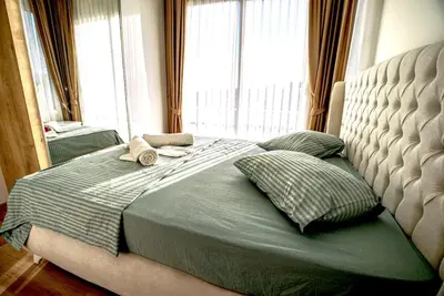 a bed in a bedroom with a large window at Spacious & Bright 2BR Apartment, 5min to Beach in Boğaz