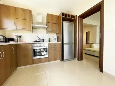 a kitchen with wooden cabinets and a refrigerator at Stylish 2BR Apartment with Balcony and Parking near Saint Lazarus and Finikoudes Beach in Larnaka