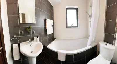 a bathroom with a tub and a sink and a toilet at Stylish 2BR Apartment with Balcony and Parking near Saint Lazarus and Finikoudes Beach in Larnaka