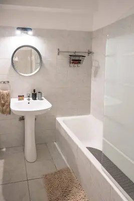 a white bathroom with a tub and a sink and a bath tub at Anteia's Seaview Suite just steps from Finikoudes Beach Larnaca in Larnaka