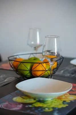 a glass of wine and a bowl of fruit on a table at Anteia's Seaview Suite just steps from Finikoudes Beach Larnaca in Larnaka