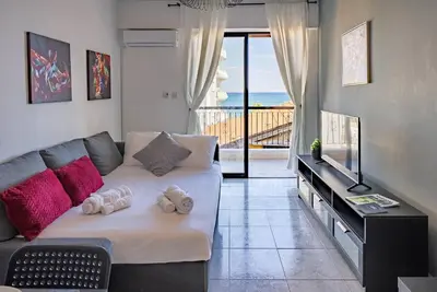 a living room with a bed and a balcony at Anteia's Seaview Suite just steps from Finikoudes Beach Larnaca in Larnaka