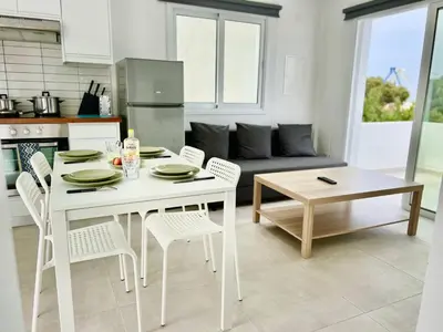 a white table and chairs in a kitchen with a couch at Protaras Cozy2bedroom Apartment in Paralimni