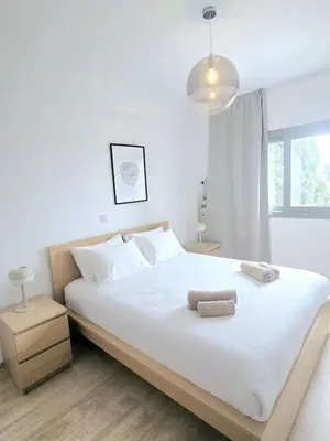 a bedroom with a large white bed with two towels on it at Crown Hall Suites in Limassol