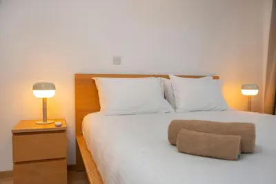 a bedroom with a bed with white pillows and two lamps at Crown Hall Suites in Limassol