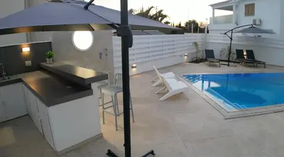 a patio with a swimming pool and an umbrella at Celestial Villa in Ayia Napa