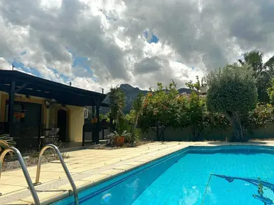a swimming pool in front of a house at Cheerful and cozy Bungalow with pool and fireplace in Athalassa