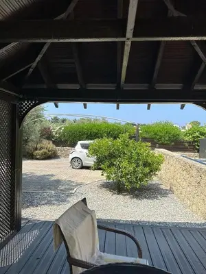 a porch with a chair and a car in a parking lot at Cheerful and cozy Bungalow with pool and fireplace in Athalassa