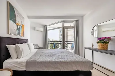 a bedroom with a large bed and a balcony at Marathon Beach Apartment - Sea View, Shared Pool in Limassol