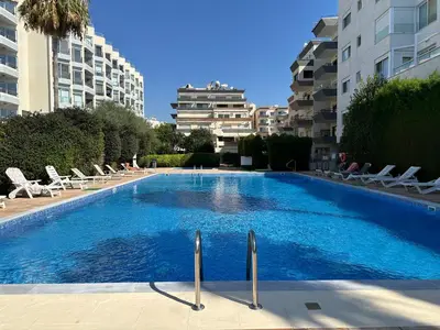 a large blue swimming pool with chairs and buildings at Beachfront apartment with Kids Room, Pool & 2 Workspaces in Limassol