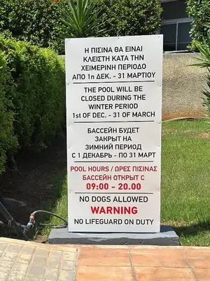 a white sign with writing on it in the grass at Beachfront apartment with Kids Room, Pool & 2 Workspaces in Limassol