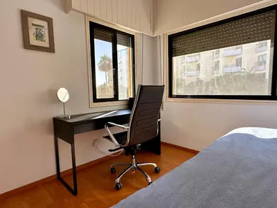 a bedroom with a desk with a chair and a bed at Beachfront apartment with Kids Room, Pool & 2 Workspaces in Limassol
