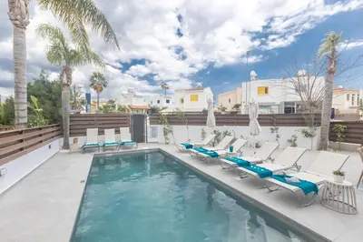 a swimming pool with chaise lounges and chairs at EvelMar Villa in Protaras