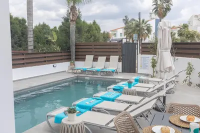 a pool with chaise lounge chairs and a swimming pool at EvelMar Villa in Protaras