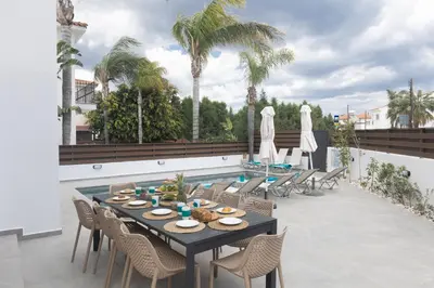 a patio with a table and chairs and a pool at EvelMar Villa in Protaras