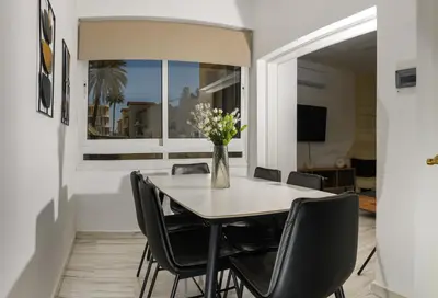 a dining room with a table with chairs and a vase of flowers at Ariel 3 bed Apartment in Larnaka