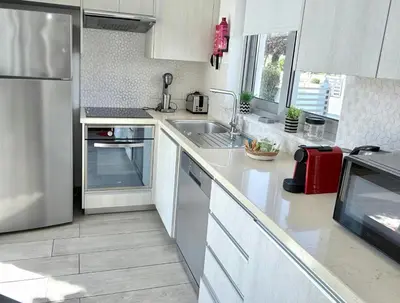 a white kitchen with a sink and a refrigerator at Too Coool Villa Milos Lifestyle in Protaras