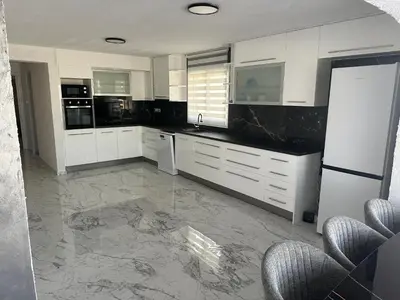 a kitchen with white cabinets and a marble floor at Emerald Luxe in Ayia Napa