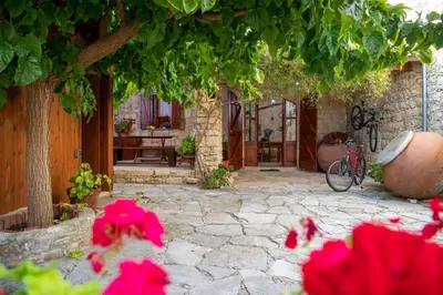 a stone patio with pink flowers in front of a building at Apanemia Inn House in Lofou