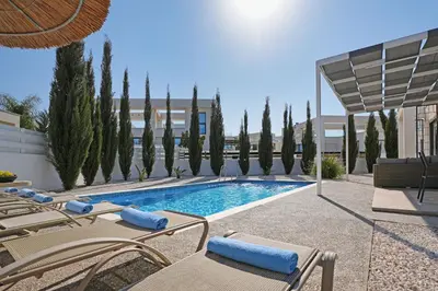 a swimming pool with lounge chairs and a building at Villa Camellia - 3bed Bungalow large pool in Protaras