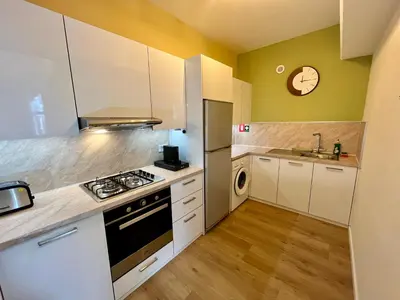 a kitchen with white cabinets and a clock on the wall at Tropical Cozy 1 - Bedroom Apartment in Limassol