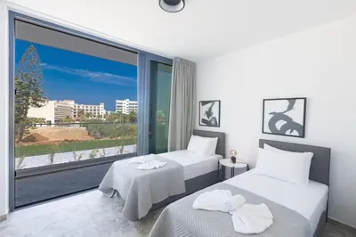 a bedroom with two beds and a large window at Protaras Aqua Villa AQ05 in Protaras