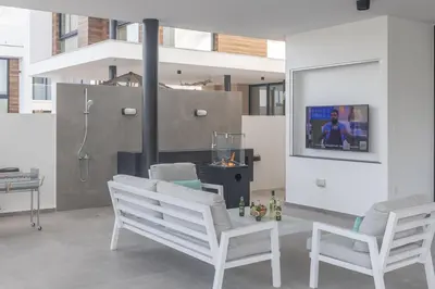 a living room with two white chairs and a fireplace at Aqua 4 Bedrooms in Paralimni