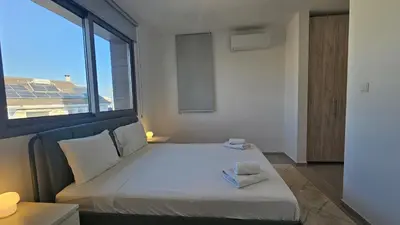 a bedroom with a large white bed with a window at STAY Larnaca Pearl Apartment in Larnaka