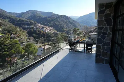 a balcony with a table and chairs and mountains at Luxury 5-Bedroom Chalet Kalopanayiotis in Kalopanayiotis