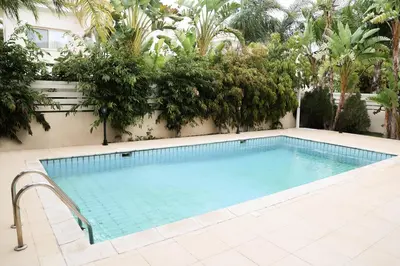a swimming pool next to a building with trees at Anthorina Villa 21 in Protaras