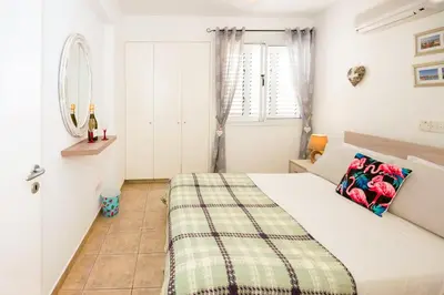 a white bedroom with a bed and a mirror at Jules Apartment in Paralimni