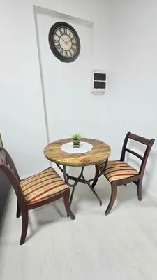 a table and two chairs with a clock on the wall at Antionette Studio Apartment in Limassol