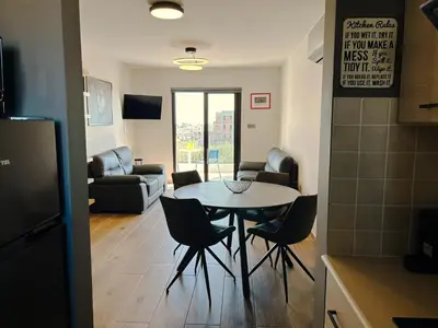 a kitchen and living room with a table and chairs at THE A-LINE SEAVIEW MALAMA APARTMENT with pool, tennis court & gym in Paralimni