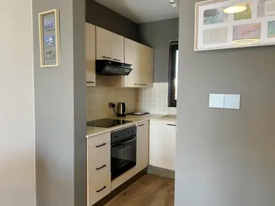 a kitchen with white cabinets and a black oven at THE A-LINE SEAVIEW MALAMA APARTMENT with pool, tennis court & gym in Paralimni
