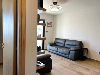 a living room with a black leather couch in a room at THE A-LINE SEAVIEW MALAMA APARTMENT with pool, tennis court & gym in Paralimni