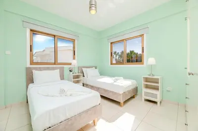 two beds in a room with two windows at Tranquility Villa in Ayia Napa
