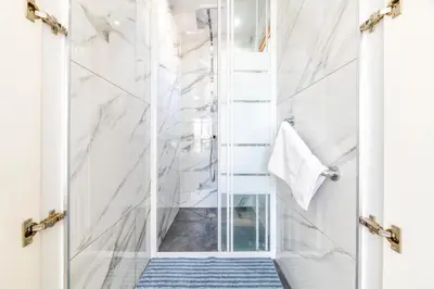 a shower with a glass door and a blue rug at Tranquility Villa in Ayia Napa