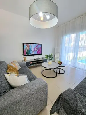a living room with a couch and a tv at SERENITY PEARL VILLA at the sea in Protaras