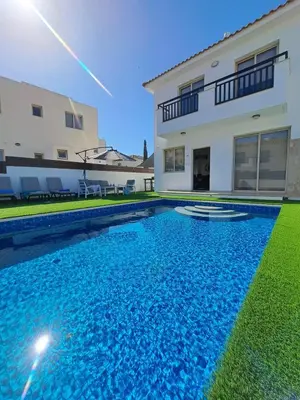 a swimming pool in front of a house at SERENITY PEARL VILLA at the sea in Protaras
