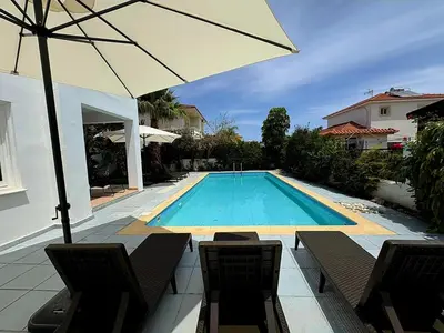 a swimming pool with two chairs and an umbrella at Villa Solmare in Pervolia