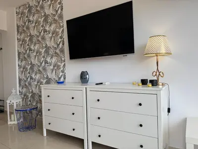 a white dresser with a flat screen tv on a wall at Protaras Sunset Bay in Protaras