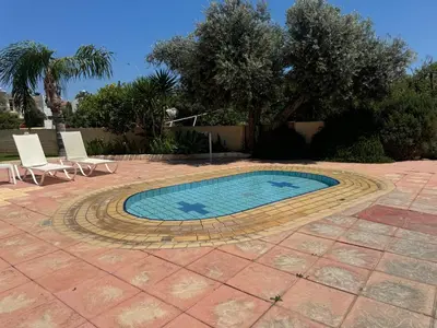 a swimming pool with two lawn chairs at Protaras Sunset Bay in Protaras