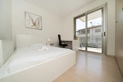 a white bedroom with a large bed and a desk at Central Luxurious 2 bedroom flat in Strovolos
