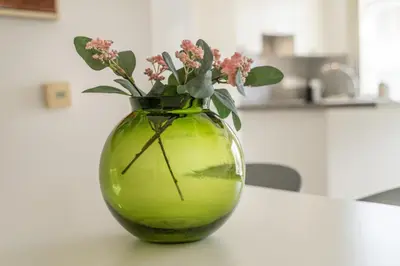 a green vase with flowers in it on a table at Central Luxurious 2 bedroom flat in Strovolos